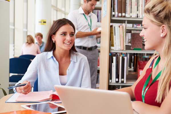 Two people talking in library