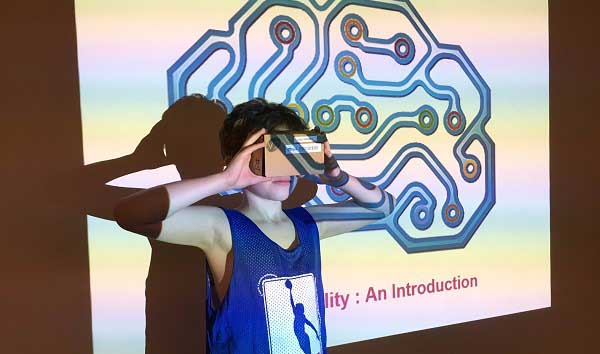 A youth at tries out the Knox V2 virtual reality cardboard viewer at TPL's Sanderson Library After School Youth Hub during March Break