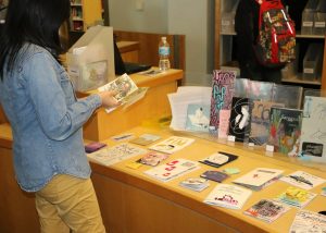 Student browsing through zines on a table at Seneca Libraries