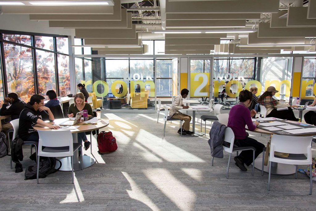 Image of a busy library interior, students working at tables.